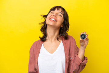 Young latin woman holding compass isolated on yellow background laughing © luismolinero