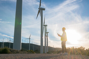 Fototapeta na wymiar Side view of engineer standing and analysis wind turbine of power generator station