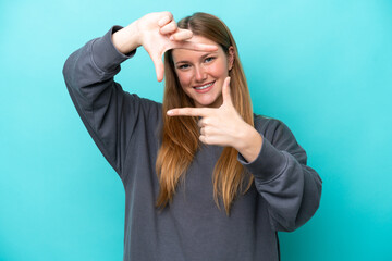 Young caucasian woman isolated on blue background focusing face. Framing symbol