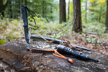 Several survival and bushcraft tools on a tree stump