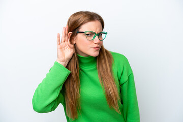 Young caucasian woman isolated on white background listening to something by putting hand on the ear