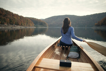 Rear view of woman paddling canoe on lake	