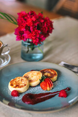 Cottage cheese pancakes or syrniki with raspberry jam on a green plate