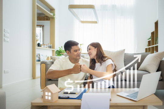 Asian couple in home or house. Include increasing graph, laptop, calculator and document on table. To bump punch with concept for market price, house value, loan, finance, real estate and property.
