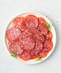 Thinly sliced salami sausage on a plate, top view