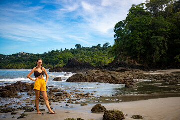 A beautiful girl in yellow shorts walks on a tropical beach with palm trees in manuel antonio national park in quepos, Costa Rica; tropical paradise beach in Costa Rica