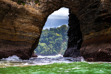 natural bridge in the rocks on the pacific coast of costa rica in marino ballena national park;...