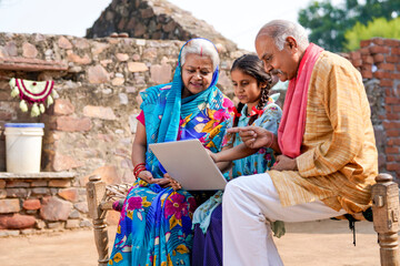 Fototapeta na wymiar Indian little girl using laptop with grandparents.