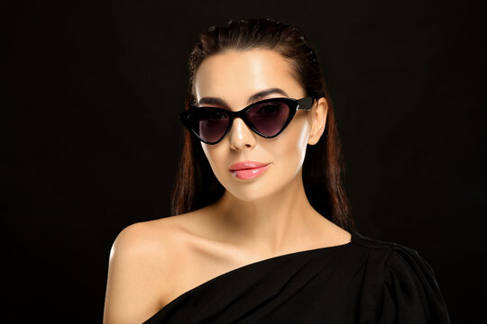 Portrait of beautiful young woman in stylish sunglasses on black background