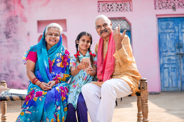 Indian little girl using smartphone with grandparents.