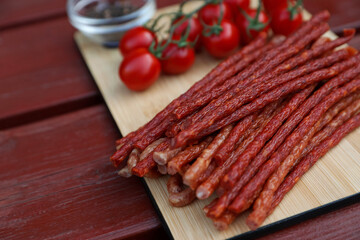 Tasty dry cured sausages (kabanosy) on wooden table, closeup. Space for text