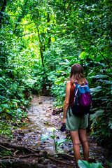 Backpacker girl walks through dense rainforest in Golfito National Wildlife Refuge; walking through wild tropical forest in Costa Rica