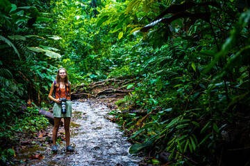 Backpacker girl walks through dense rainforest in Golfito National Wildlife Refuge; walking through wild tropical forest in Costa Rica