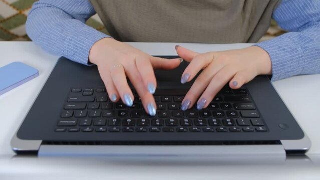 Overhead 4k video of young woman typing text on a computer keyboard. Female programmer person coding on a modern notebook pc behind a white table, filmed from above
