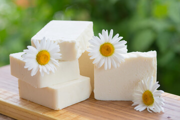 Obraz na płótnie Canvas White handmade soap with chamomile flowers on a green background