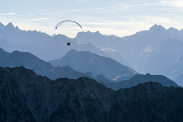 Paraglider flying above blue Mountains Silhouette, Allgaeu, Oberstdorf, Alps, Germany. Travel...