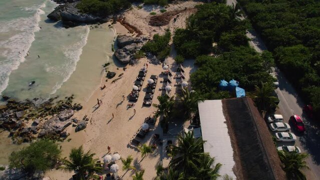 Aerial orbiting shot of tourist on sandy beach Relaxing and enjoying good weather in Tulum in front of Caribbean Sea