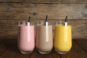 Glasses with different smoothies on wooden table