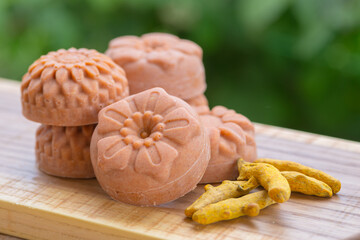  Round orange soap in the form of flowers with turmeric on a green background