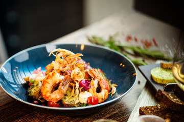 Warm salad with Argentinian king prawns. Almond potato, mini romaine lettuce, carrot, cherry tomato, pesto, black root chips, caramelized walnut, beet balsamic. Food served in modern restaurant