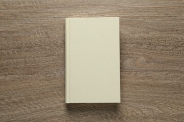 Closed hardcover book on wooden table, top view