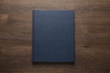 Closed hardcover book on wooden table, top view