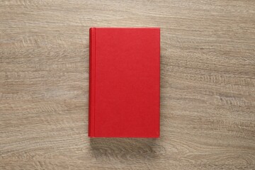 Closed hardcover book on wooden table, top view