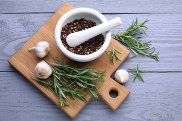 Fresh rosemary, mortar and garlic on wooden table, flat lay