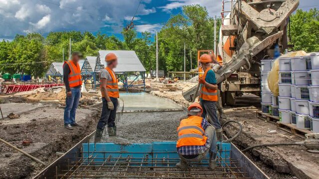 Concrete pouring in metal reinforcement for road construction with many workers in uniform, excavators and mixer machine timelapse. Reconstruction of tram tracks
