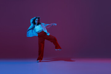 Flexible young girl, contemp dancer dancing hip-hop or experimental dance isolated on dark purple...