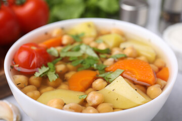 Tasty chickpea soup in bowl on table, closeup