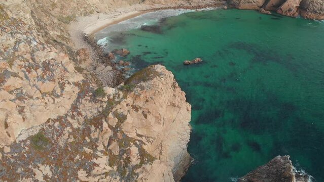 Drone footage of remote beach with its wide sandy coast. Stormy sea washing wild and unspoiled cliffs with natural beauty around. Europe, Portugal, Ursa Beach. High quality 4k footage