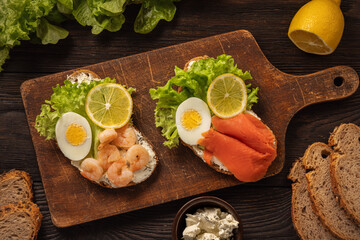 The toasts with boiled eggs, salad lettuce, lemon slime, shrimps and smoked salmon.