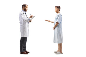 Full length profile shot of a male doctor and a young male patient in a hospital gown standing and talking