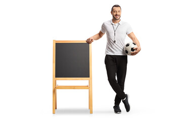 Physical education teacher holding a football and leaning on a blackboard