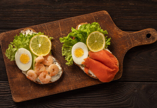 The toasts with boiled eggs, salad lettuce, lemon slime, shrimps and smoked salmon.