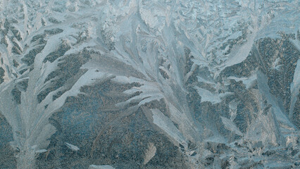 Close-up of ice patterns on the window glass on winter day, textured snowy background