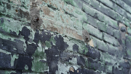 Old brick wall, old facade, wall of the old house, brick, green and black. Peeled paint. Defocus. Wall with screwed rusty bolts