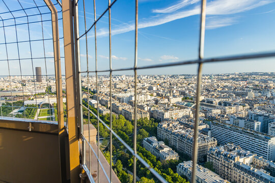 View on the city of Paris through the metal protective grid of the second floor of the Eiffel Tower