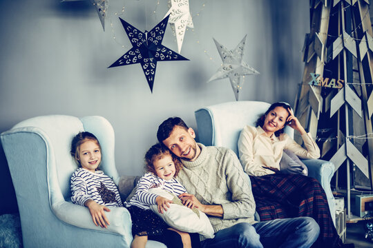 Happy Family Sitting In The Living Room Christmas Evening.