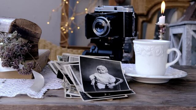 candle burning, old family photos in vintage interior, stack nostalgic sentimental pictures, vintage photographs 50s, 40s, retro accordion camera on wooden table, concept genealogy, family tree