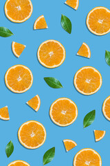 Summer flat lay pattern made with fresh orange fruit slices and green leaves on vibrant blue background. Minimal sunlight concept with sharp shadows. - 552596948