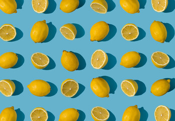 Summer pattern made with fresh cut and whole yellow lemon on bright light blue background. Minimal background summer concept on with harsh light and sharp shadow - 552596952