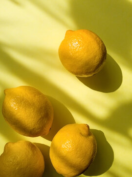 Composition with whole ripe yellow lemons on bright yellow blue background. Summer time flat lay with daylight and sharp shadows. Top view