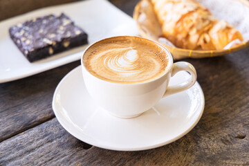Coffee cup with pattern in the white cup on wooden background.
