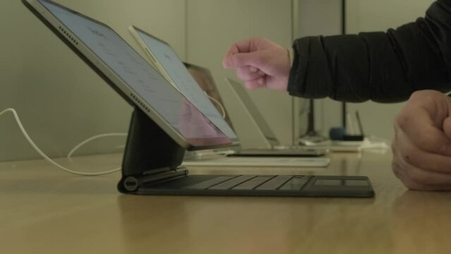 male customer testing new tablet in apple sales office in Germany, products, accessories modern retail store with exhibition gadgets, samples, people, buyers came to buy, Frankfurt - December 2022