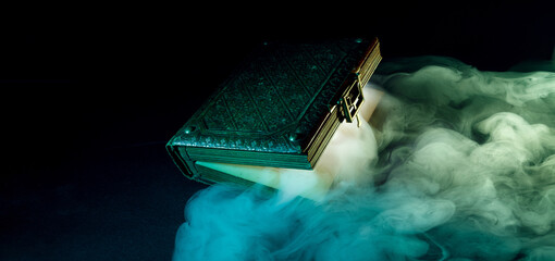 Mysterious glowing antique book on a dark background. Horizontal banner with copy space for popular...