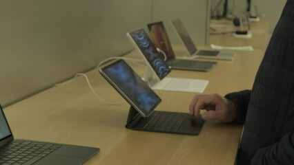 male customer testing new tablet in apple sales office in Germany, products, accessories modern retail store with exhibition gadgets, samples, people, buyers came to buy, Frankfurt - December 2022