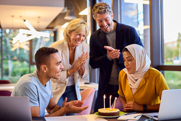 Staff Celebrating Birthday Of Female Colleague Wearing Headscarf In Office With Cake