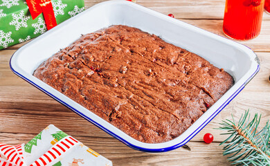 Christmas brownies with walnut and cranberry on rustic wooden background. Fir tree branches and Christmas decorations.